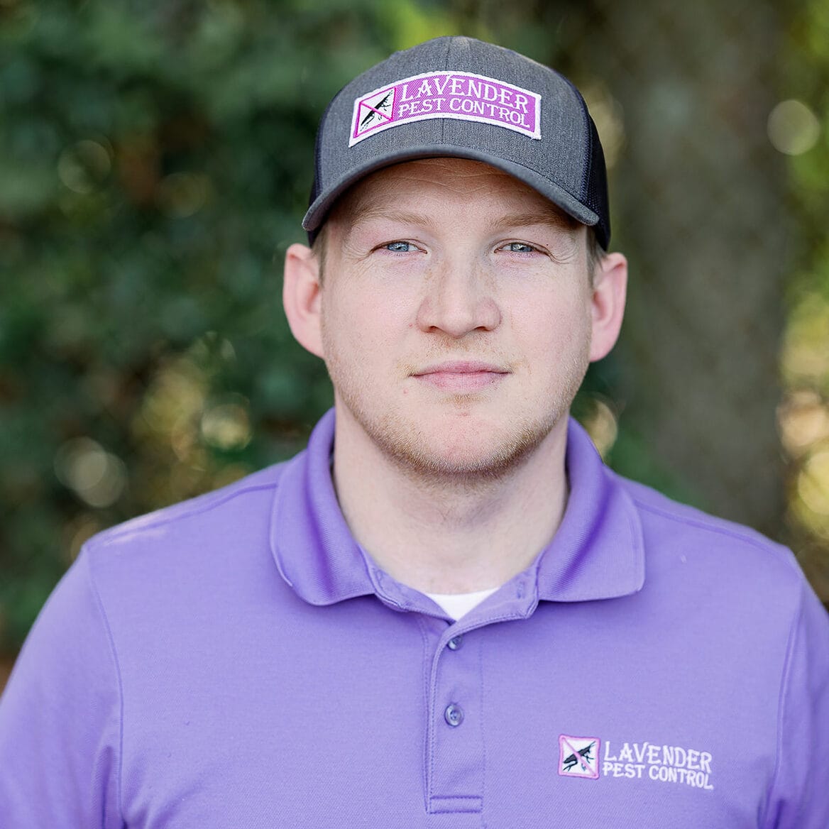 Person wearing a Lavender Pest Control cap and polo shirt outdoors.