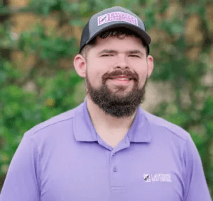 Person wearing a lavender pest control uniform outside.