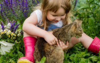 Girl hugging cat in garden with flowers