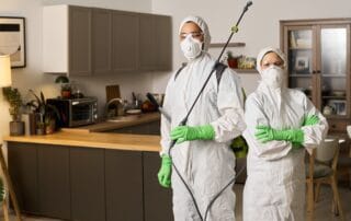 Pest control workers spraying insecticide in kitchen