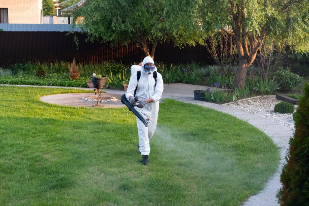 Person spraying pesticide on green lawn